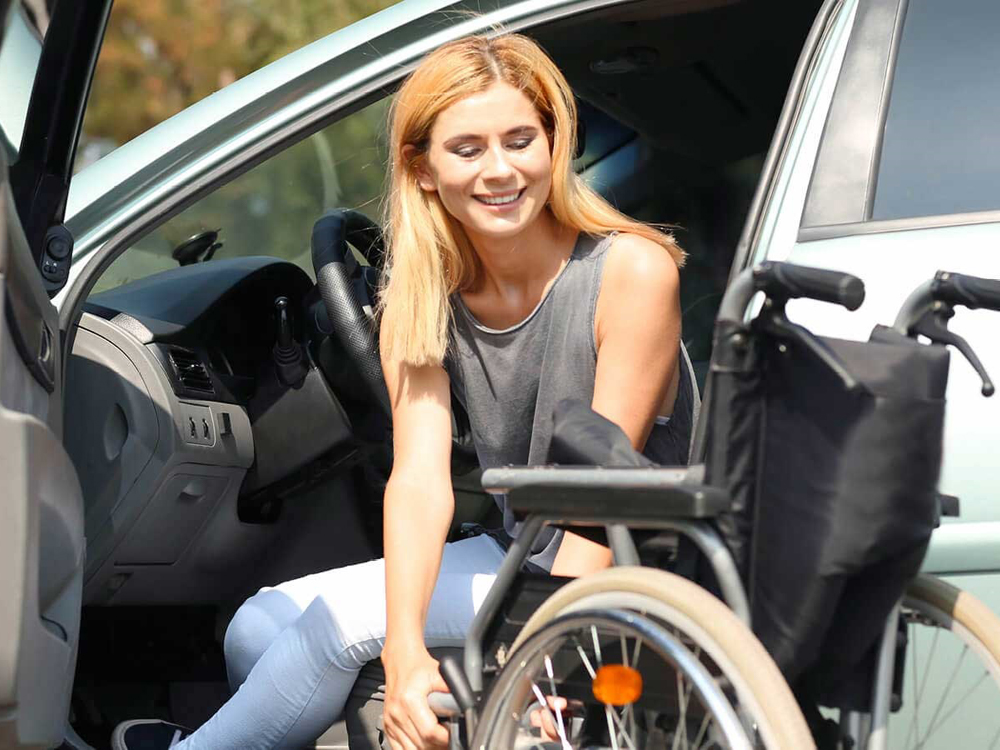 Una ragazza disabile in sedia a rotelle sale in auto